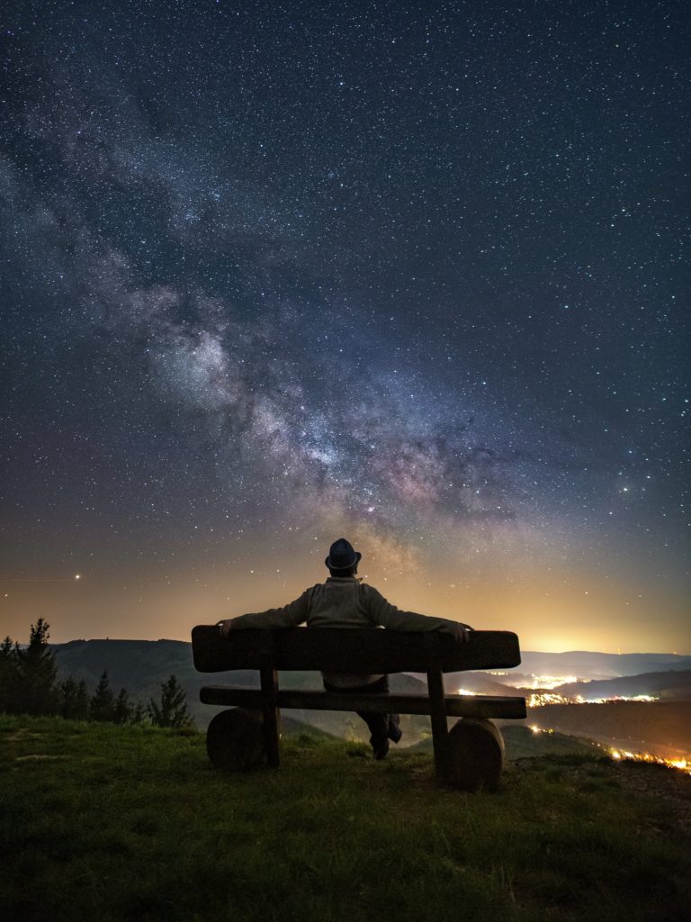 man and woman sitting on bench under starry night